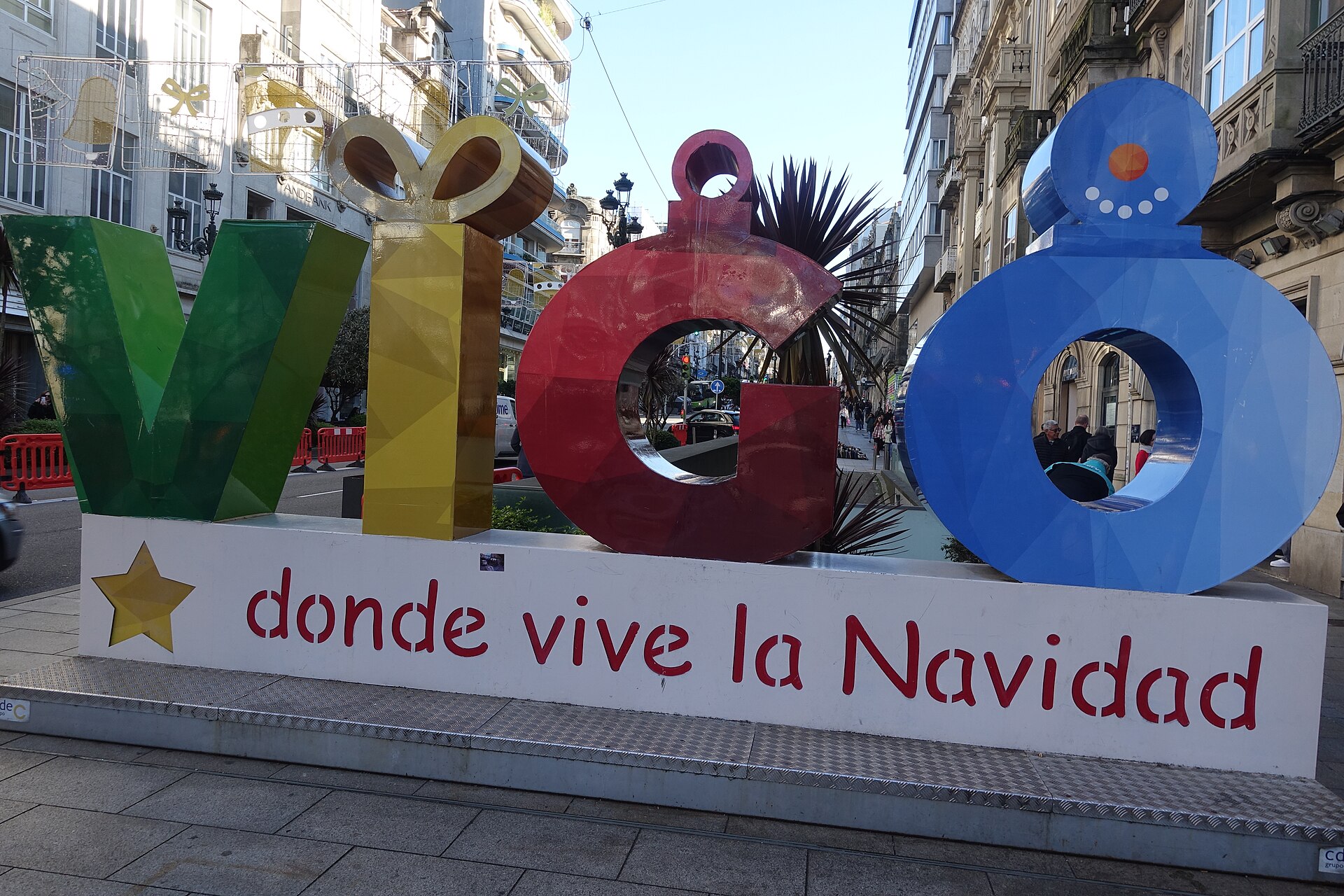 Letras gigantes de colores que forman la palabra VIGO con el lema donde vive la Navidad, en una calle del centro de Vigo, de día