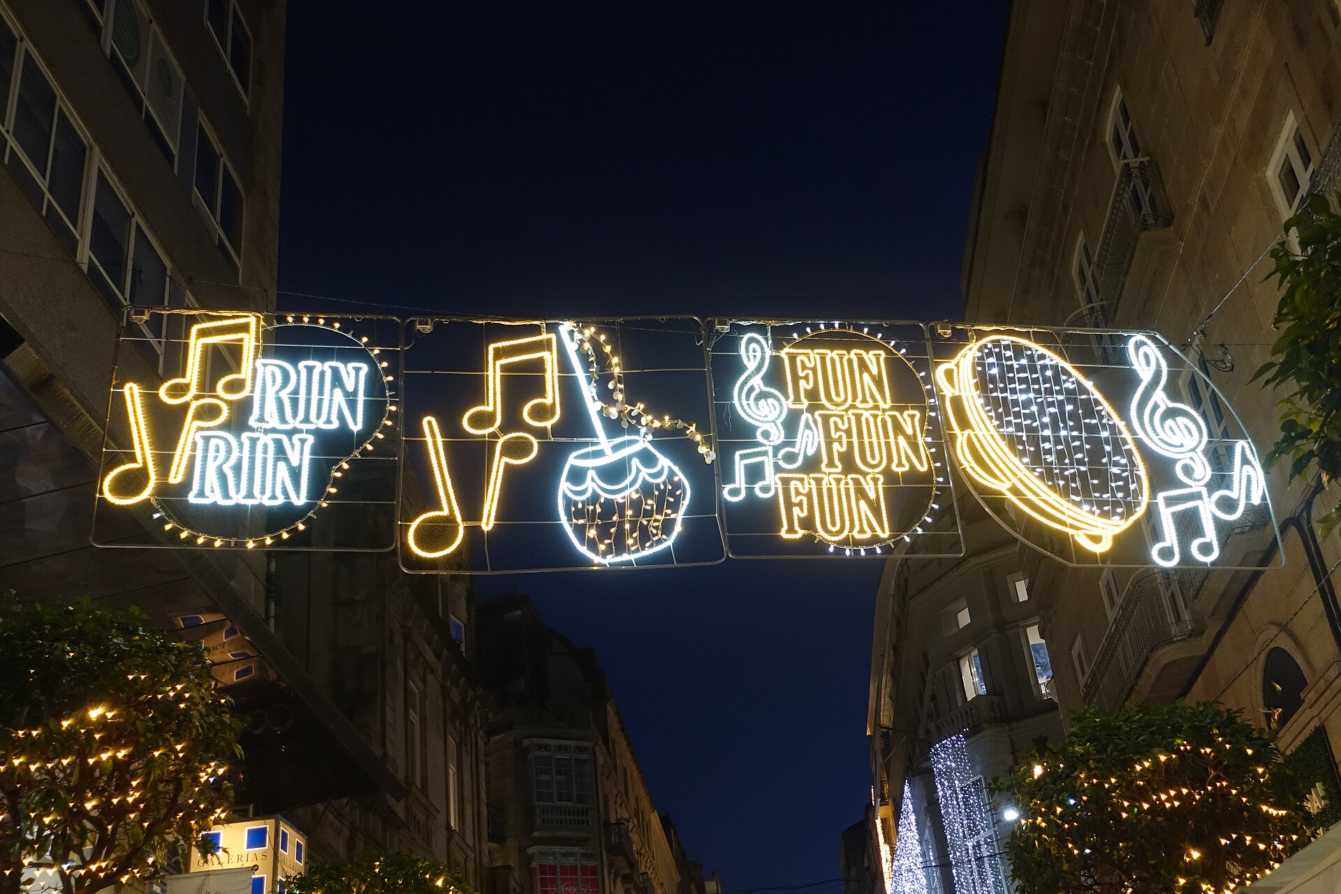 Arco de luces navideñas con notas musicales sobre una calle del centro de Vigo, de noche.
