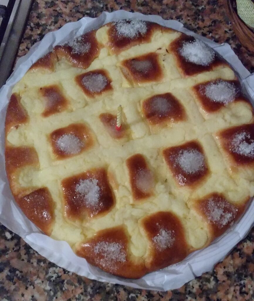 Tarta larpeira entera sobre papel de horno, con cuadrícula dorada y montones de azúcar en cada porción